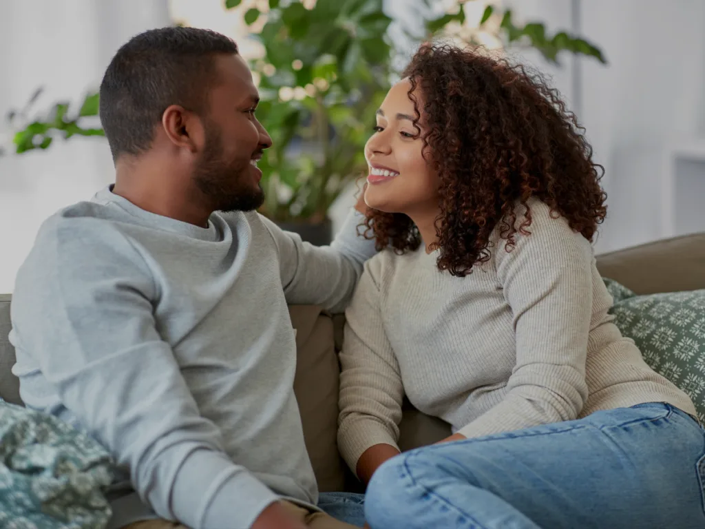 Couple talking together on a couch with warm eye contact.